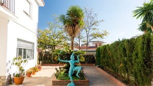Un patio con una estatua, plantas en macetas y un edificio con ventanas de rejas.