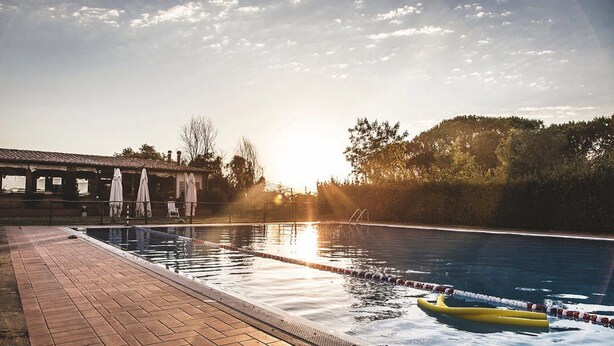 A swimming pool with lane dividers, a yellow float, and a brick deck. - Country Resort Al Poggio dei Papi (Citta della Pieve)