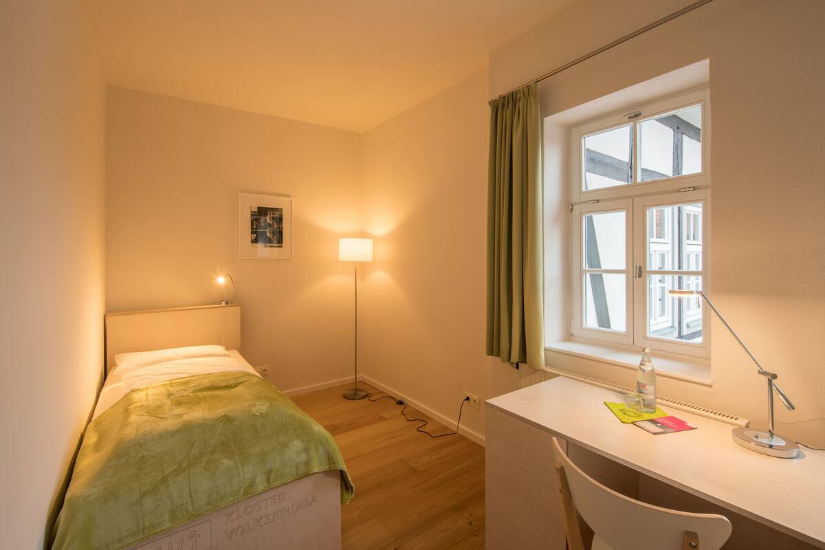 A small room with a bed, desk, and window.