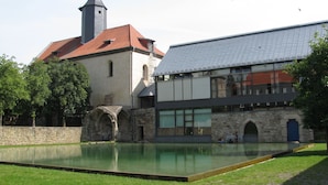 A historic building with a church tower and a modern extension with large windows. - Kloster Volkenroda (Körner)