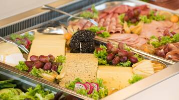 Een buffet met diverse kazen, vleessoorten en fruit.