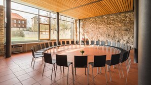 A conference room with a round table, black chairs, and a stone wall. - Kloster Volkenroda (Körner)
