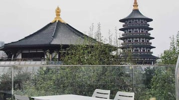 Una terraza en la azotea con una mesa y sillas, con vistas a edificios de estilo pagoda tradicional.