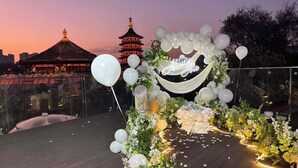 A decorated outdoor area with a floral arrangement and balloons, a sign that says "Happy," and a pagoda in the background. - First Sight Hotel,Next to Yingtianmen Imperial City,Provide Airport and High-Speed Rail Station Pickup (Luoyang)