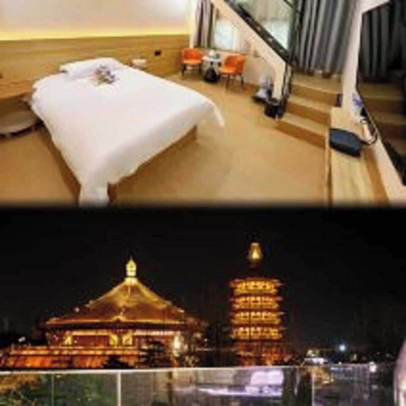 A hotel room with a bed, a small table, and a chair. There is a staircase leading to an upper level.