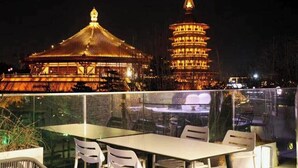 A hotel room with a neatly made bed, a bedside table, and a window with curtains. The room has a warm, inviting ambiance with soft lighting. - First Sight Hotel,Next to Yingtianmen Imperial City,Provide Airport and High-Speed Rail Station Pickup (Luoyang)