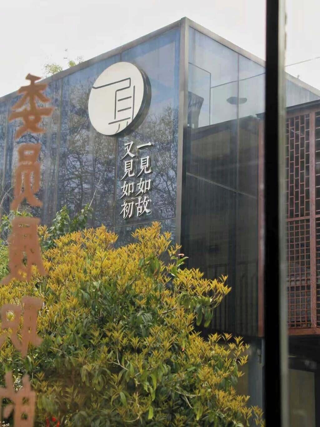 Een modern gebouw met een grote glazen gevel en een bord met Chinese karakters.