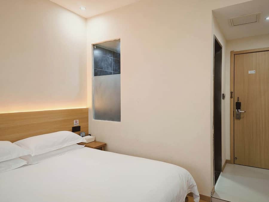 Una habitación de hotel con cama, mesita de noche, espejo y puerta.