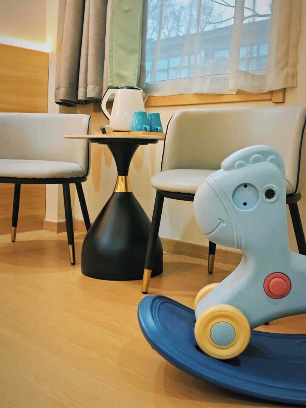 A room with a dining table, chairs, a decorative lamp, and a toy horse.