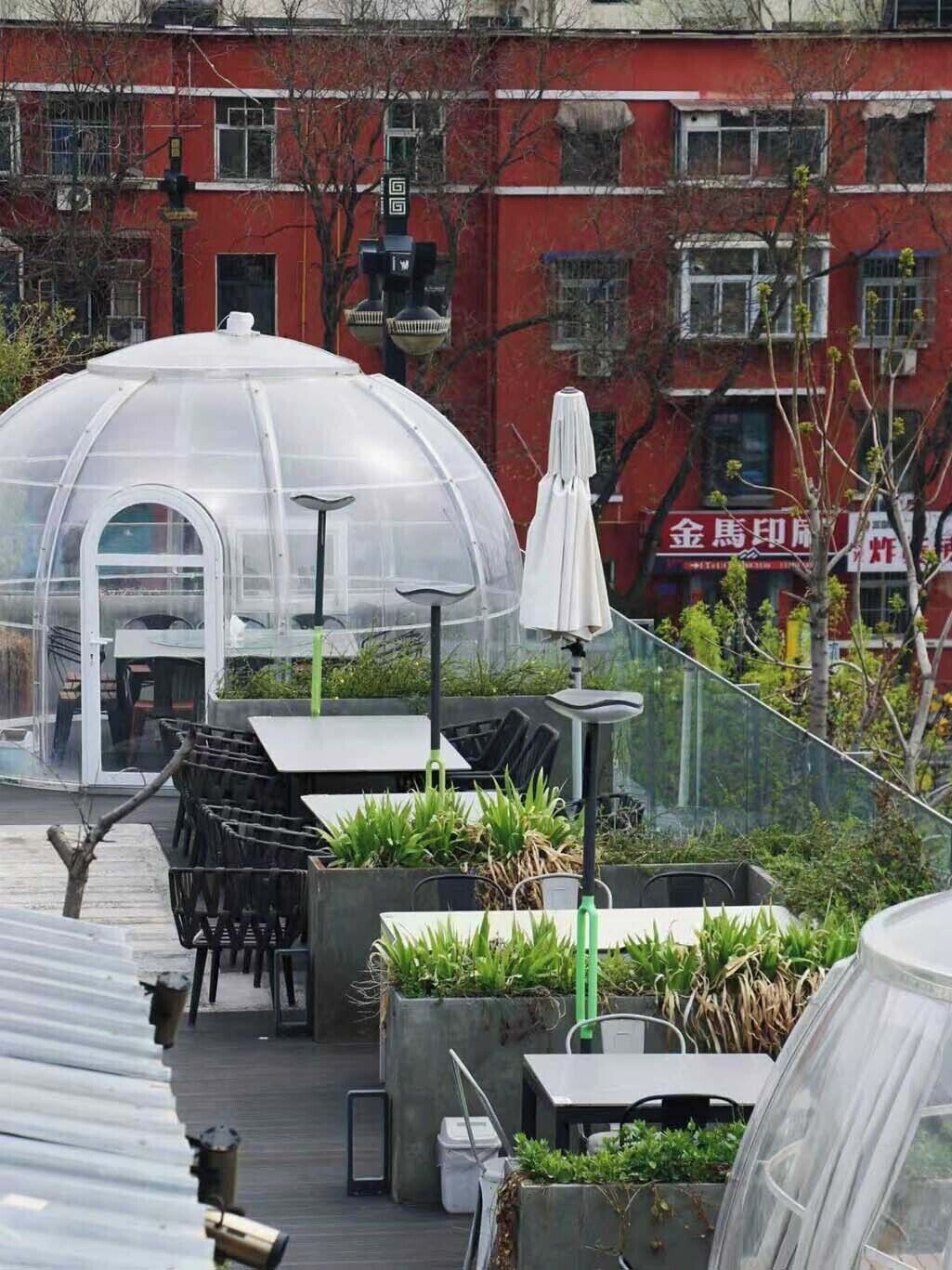 A rooftop garden with a greenhouse, outdoor seating, and potted plants.
