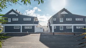 Un edificio residencial de diseño simétrico, con estructuras de dos pisos y una entrada central.