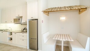 Una cocina moderna con armarios blancos, un refrigerador de acero inoxidable, un microondas y un estante de madera sobre una banca.