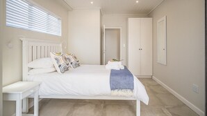 Un dormitorio con cama, mesita de noche y ventana con persianas.