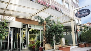 The exterior of Anka Hotel with a glass entrance, palm trees, and potted plants. - Anka Premium Hotel (Istanbul)