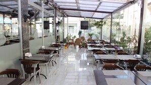 A restaurant with a glass ceiling, tables, chairs, and potted plants. - Anka Premium Hotel (Istanbul)