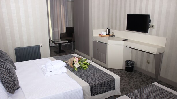 A hotel room with two beds, a desk, a TV, and a small kitchenette. - Anka Premium Hotel (Istanbul)