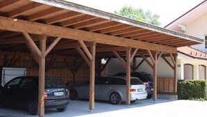 A covered parking area with three cars parked under a wooden structure. - Ferienwohnung Nr. 4 für 2 - 4 Personen 55 qm (Kiefersfelden)