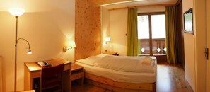 A cozy room with a wooden bed, a desk with a chair, and two wall-mounted lamps. - Berghotel Pine (Tires)