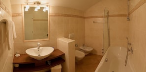 A bathroom with a sink, mirror, bidet, toilet, and bathtub. - Berghotel Pine (Tires)