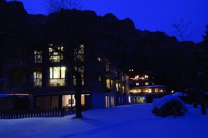 A multi-story building with large windows and a balcony, surrounded by snow. - Berghotel Pine (Tires)