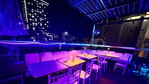 An outdoor dining area with tables and chairs, illuminated by purple lighting. - An Nam Corner Dreamer (Ho Chi Minh City)