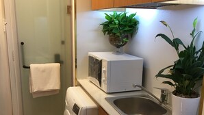 A compact kitchen with a washing machine, microwave, sink, and dishwasher. - An Nam Corner Dreamer (Ho Chi Minh City)