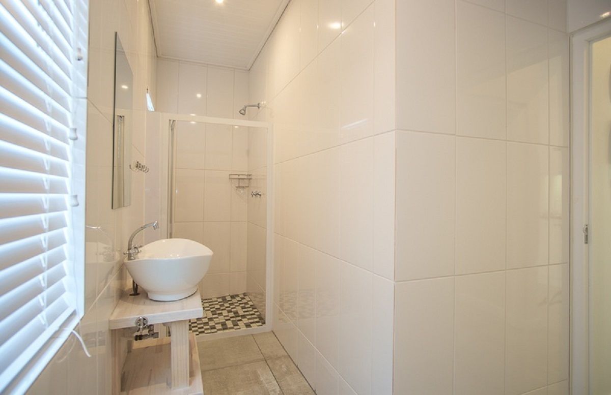 Een moderne badkamer met een wit wastafelmeubel, een douche en een zwart-wit betegelde vloer.