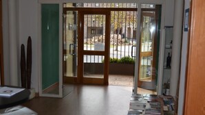 A hotel lobby with a wooden floor, a reception desk, and a glass door leading outside. - Hotel Rural Luna Llena (Torremocha de Jarama)