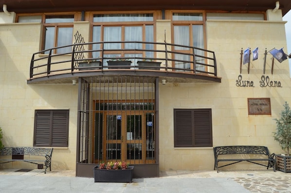 Entrada de un hotel con un balcón, un letrero que dice "Luna Elena" y una placa que indica que es un hotel.