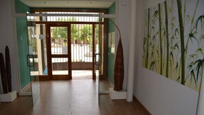 A hallway with a glass door leading to an outdoor area, a bamboo-themed wall painting, and a tall, slender sculpture. - Hotel Rural Luna Llena (Torremocha de Jarama)