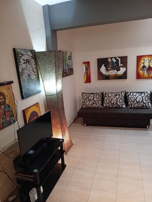 Una sala de estar con un sofá, obras de arte en las paredes y un televisor.