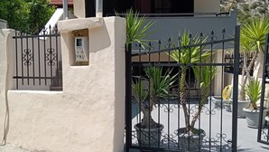 A house with a tiled roof, a gated entrance, and potted plants. - Maisonette Maria - for tranquility. Sykia Chalkidikis (Sithonia)