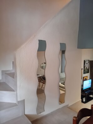 A staircase with white walls and a blue accent wall, leading to a room with a television and a framed picture. - Maisonette Maria - for tranquility. Sykia Chalkidikis (Sithonia)