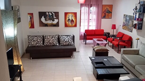 A living room with a sofa, red chairs, a coffee table, and artwork on the walls. - Maisonette Maria - for tranquility. Sykia Chalkidikis (Sithonia)