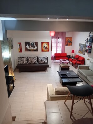 A living room with a sofa, red chairs, a coffee table, and artwork on the walls. - Maisonette Maria - for tranquility. Sykia Chalkidikis (Sithonia)