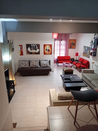 A living room with a sofa, red chairs, a coffee table, and artwork on the walls.. Maisonette Maria - for tranquility. Sykia Chalkidikis