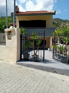 A building with a tiled roof, a gated entrance, and potted plants.