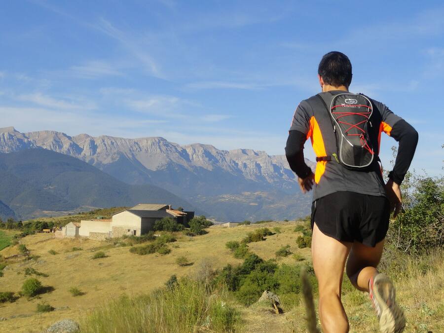 A runner on a trail with mountains in the background.