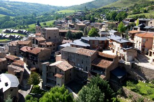 Un pueblo histórico con edificios de piedra, calles estrechas y una imponente torre de iglesia.