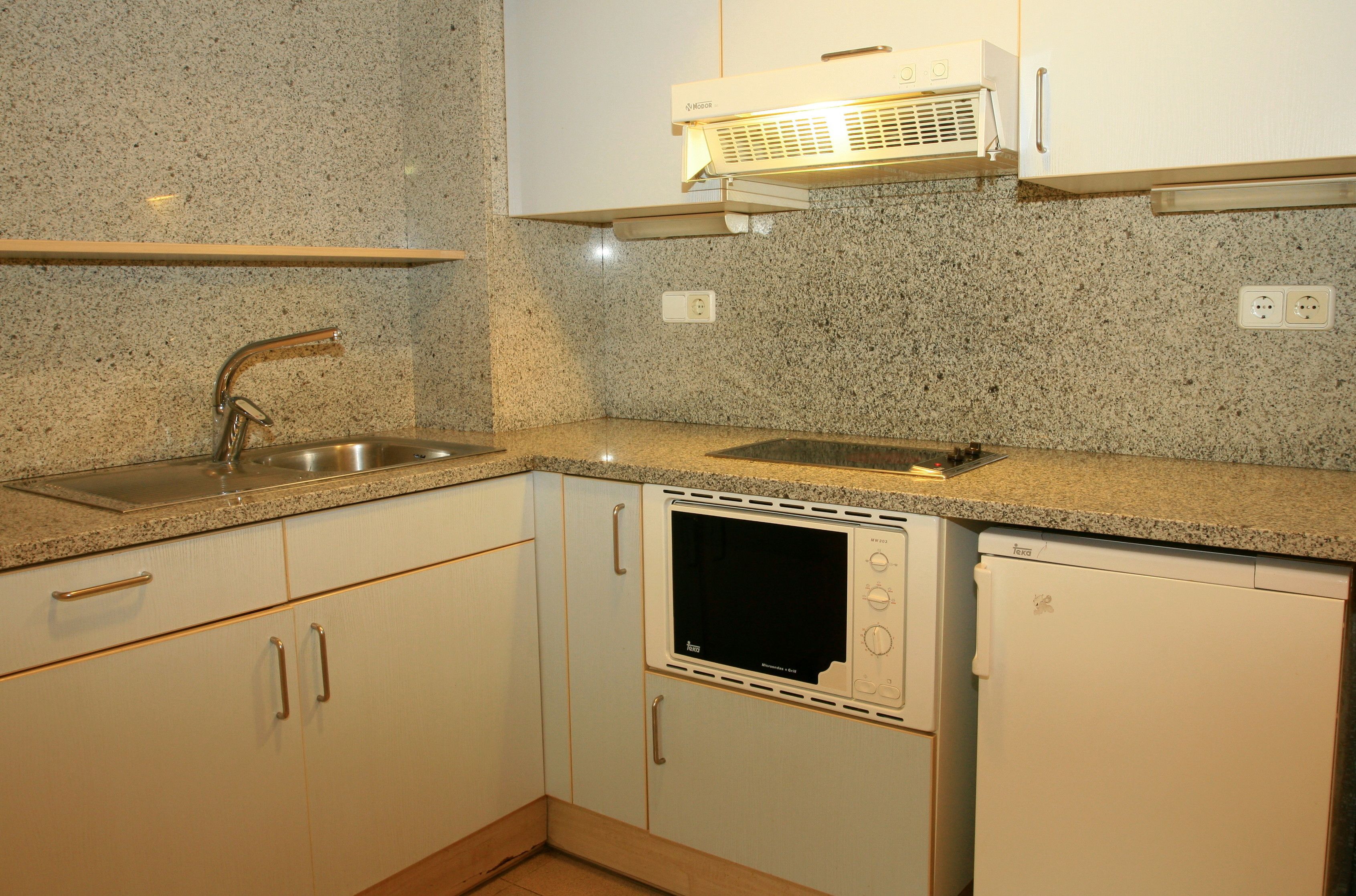 A kitchen with granite countertops, a built-in microwave, a dishwasher, and a stainless steel sink.