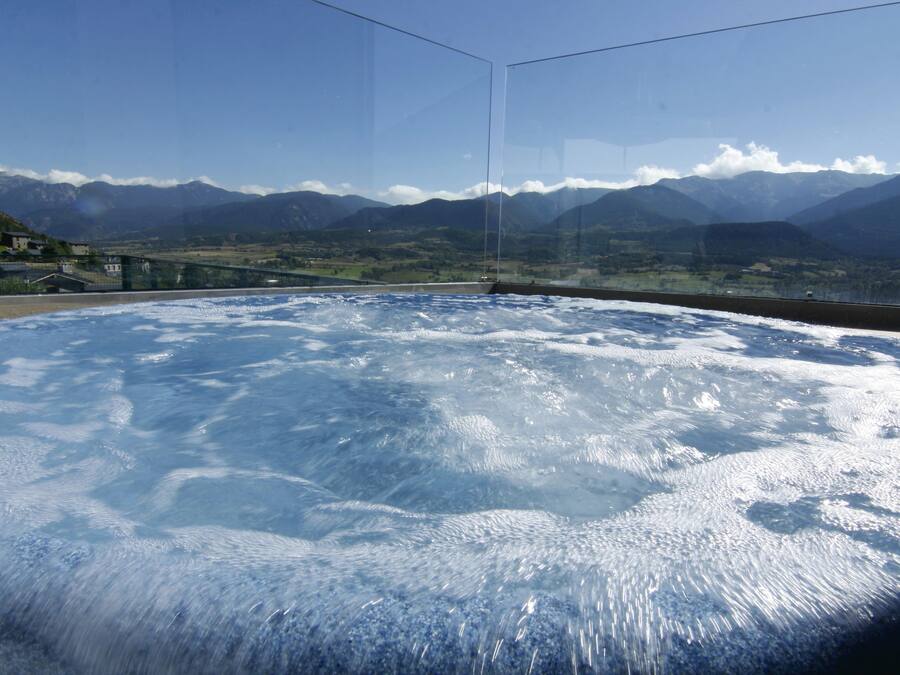 A hot tub with a view of mountains and a bridge.