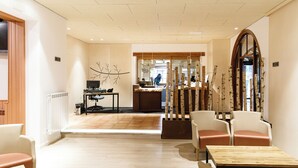 Un moderno vestíbulo de hotel con mostrador de recepción, zona de estar y un amplio ventanal de arco.