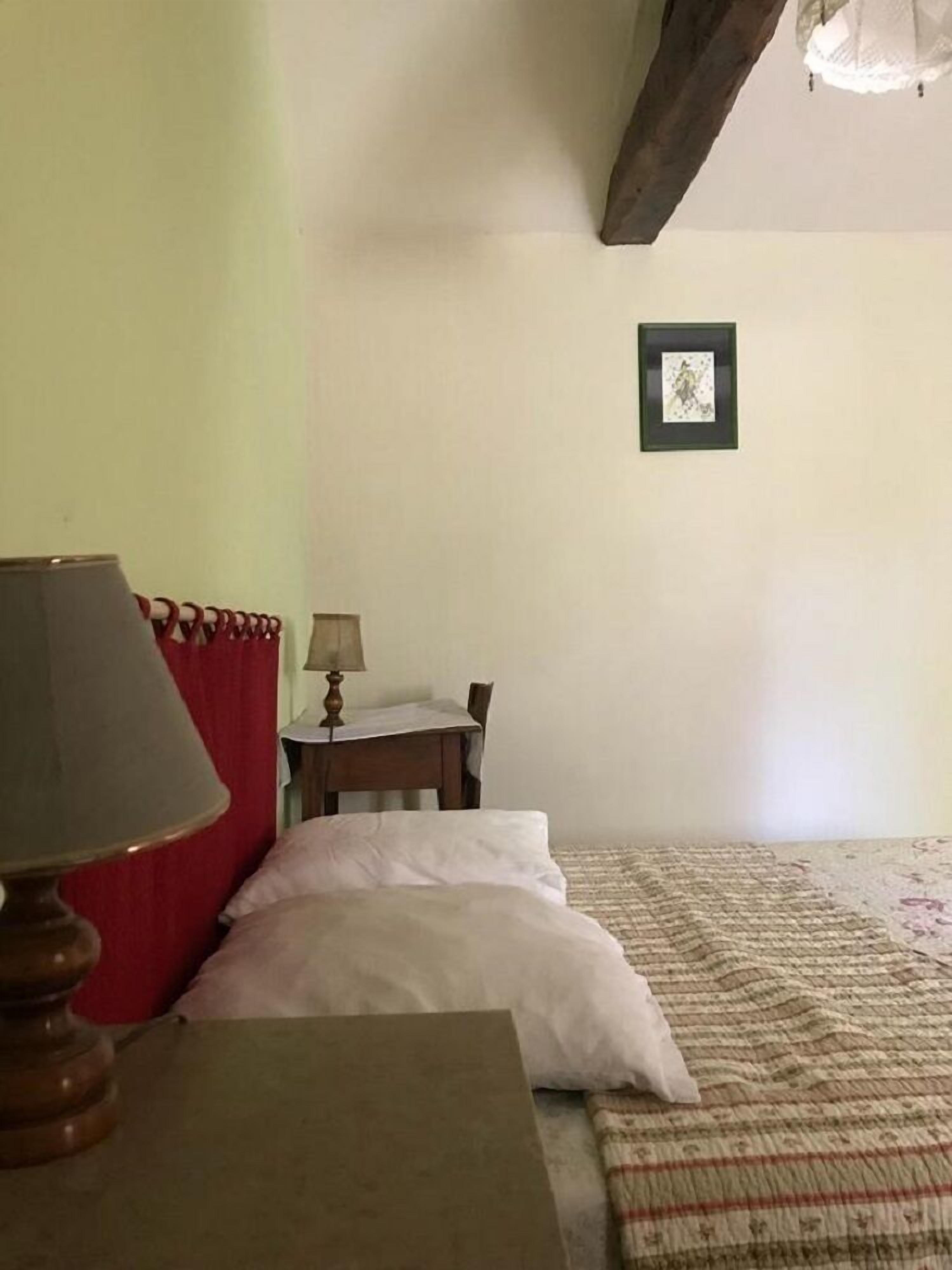 Une chambre à coucher avec un lit, une table de chevet, une lampe et un tableau encadré au mur.