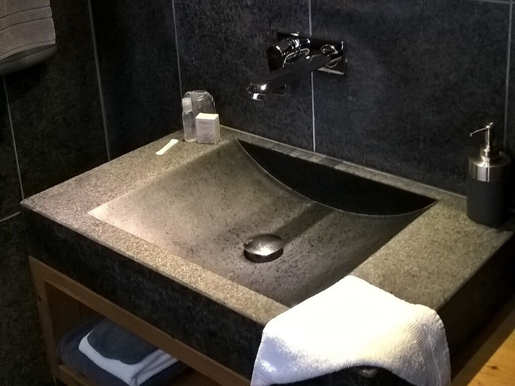 Ein Badezimmer mit Marmorwaschtisch, Wasserhahn und Seifenspender.