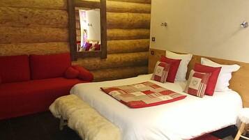 Un dormitorio de estilo cabaña de madera con una cama, un sofá rojo y un banco.