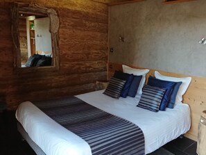 Una habitación tipo cabaña de madera con una cama, un espejo y un cabecero de madera.
