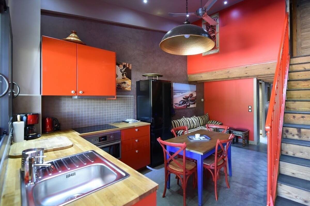 A compact kitchen with a sink, stove, and dining area with chairs.