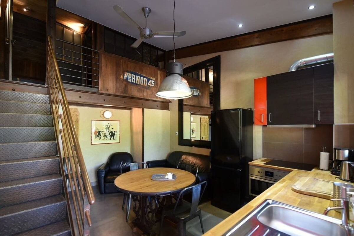 A modern kitchen with a dining area, a staircase, and a sign reading "Pernon 45".