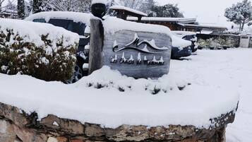 Un segnale di pietra ricoperto di neve con l'iscrizione "Les Cheneaux de Maromme" di fronte a un edificio.