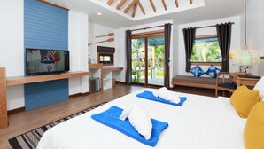 A modern hotel room with a large bed, a TV, a desk, and a balcony with a view of palm trees.